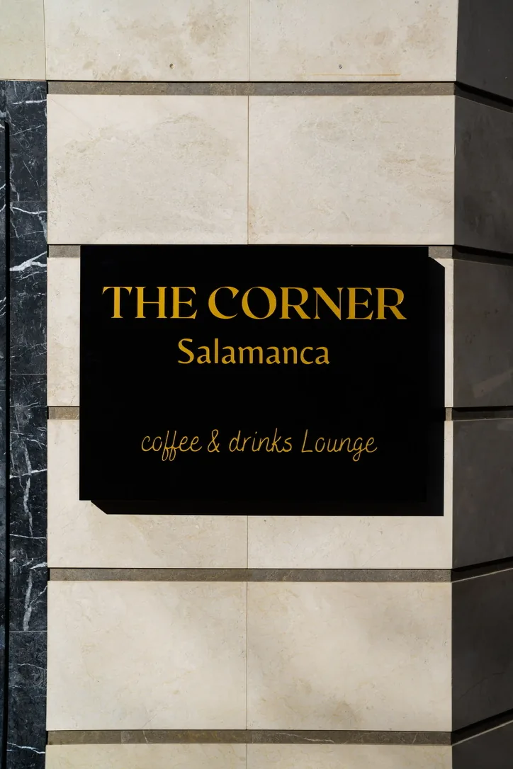 The Corner Salamanca sign on the stone facade of the café.