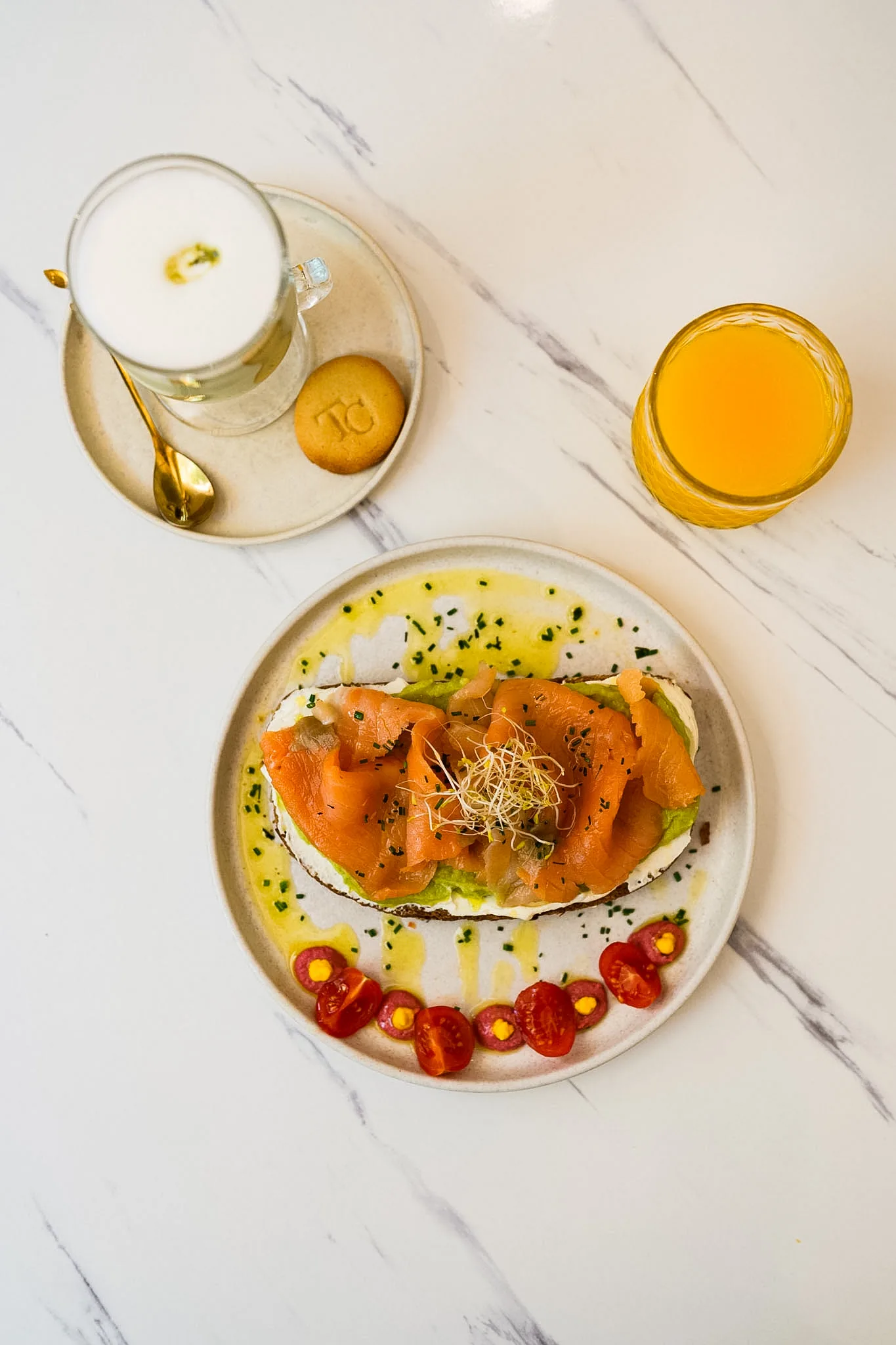 Salmon and avocado toast served with juice and a cold drink.