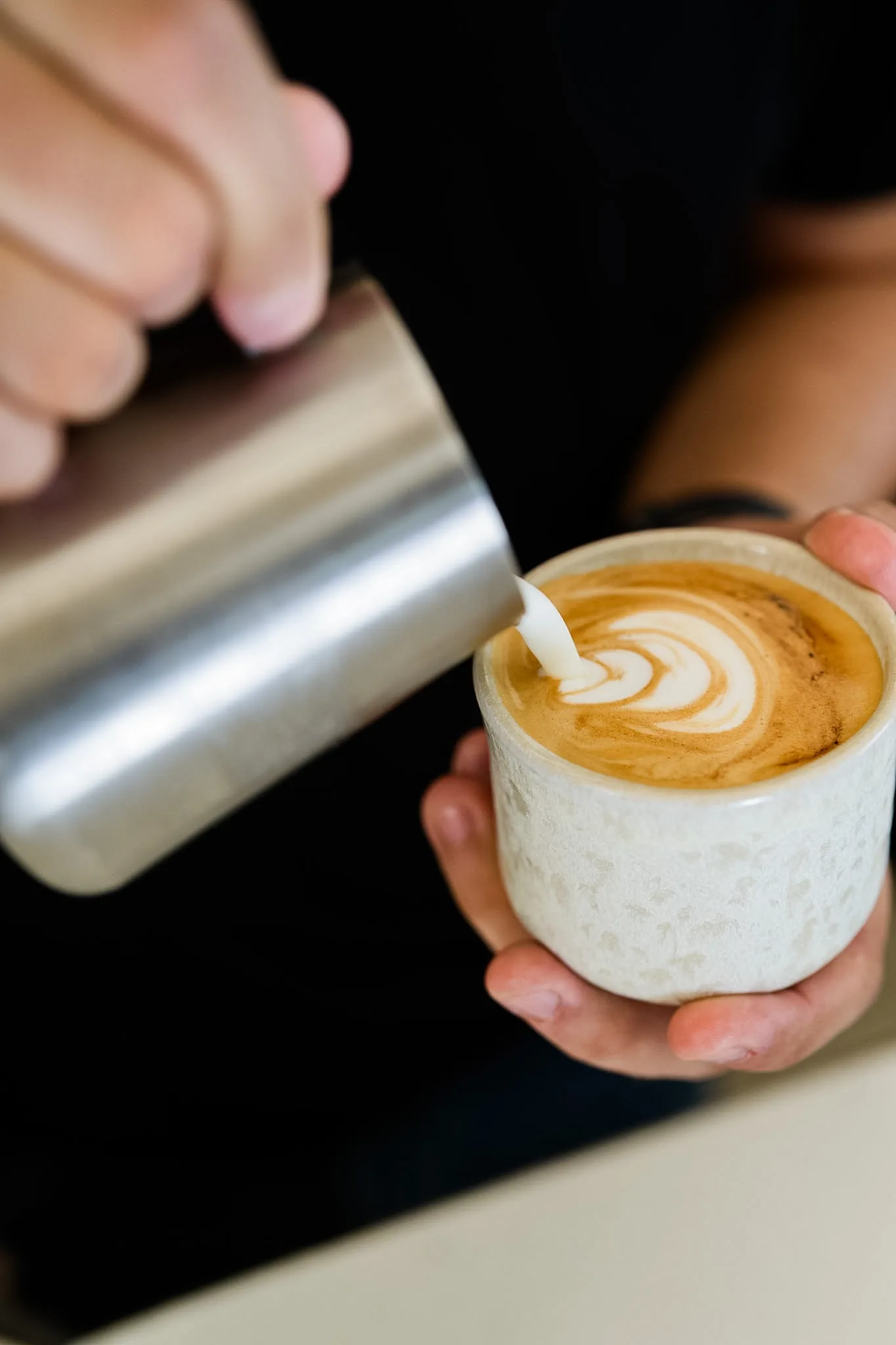 Milk being poured into a handmade cup to finish a latte.