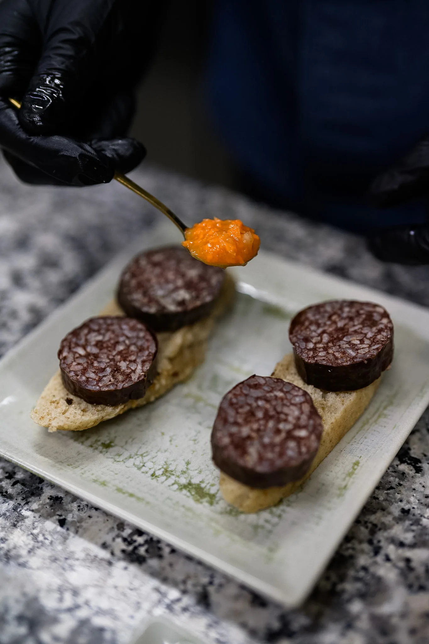 A member of the kitchen team finishing a plate by hand.