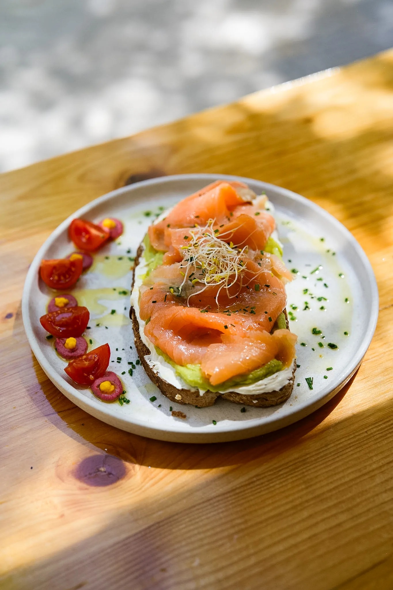 Salmon toast with avocado, cream cheese, sprouts and tomatoes.